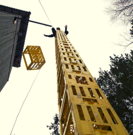 Bilde av en høy stabel med bruskasser, og en person på toppen av bruskassene.