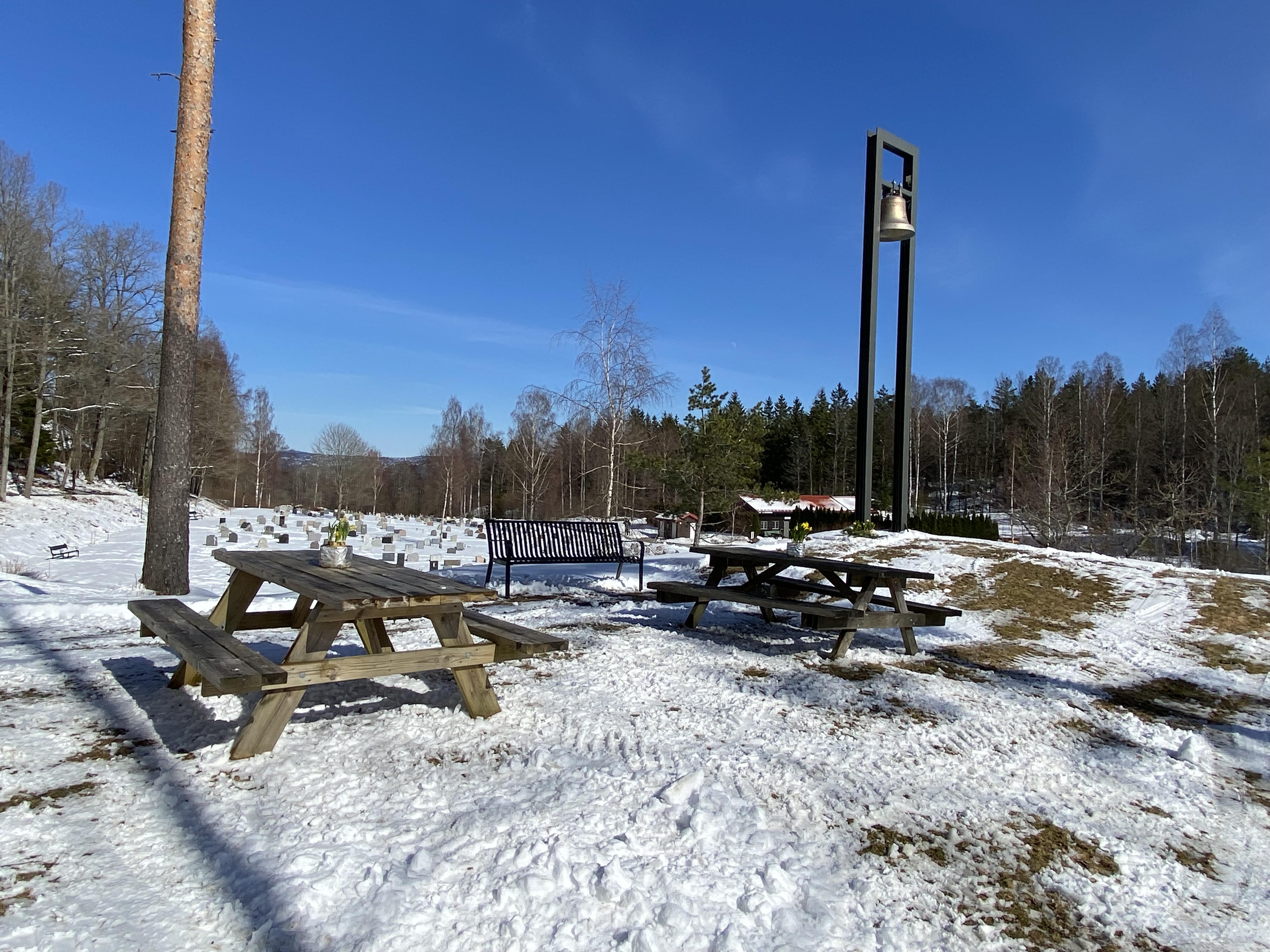 Klokketårnet ved Nesodden kirke med to benker. Bildet av Bjørn Egil Kihlstrøm.