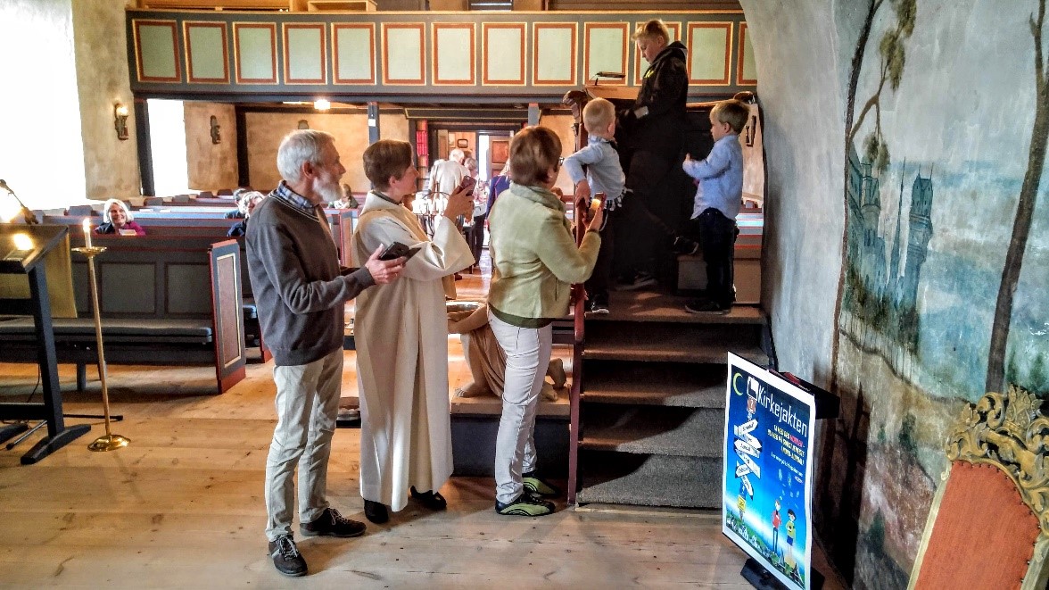 Folk i alle aldre med mobilen på kirkejakt i Ulnes kyrkje 17. juni 2018.