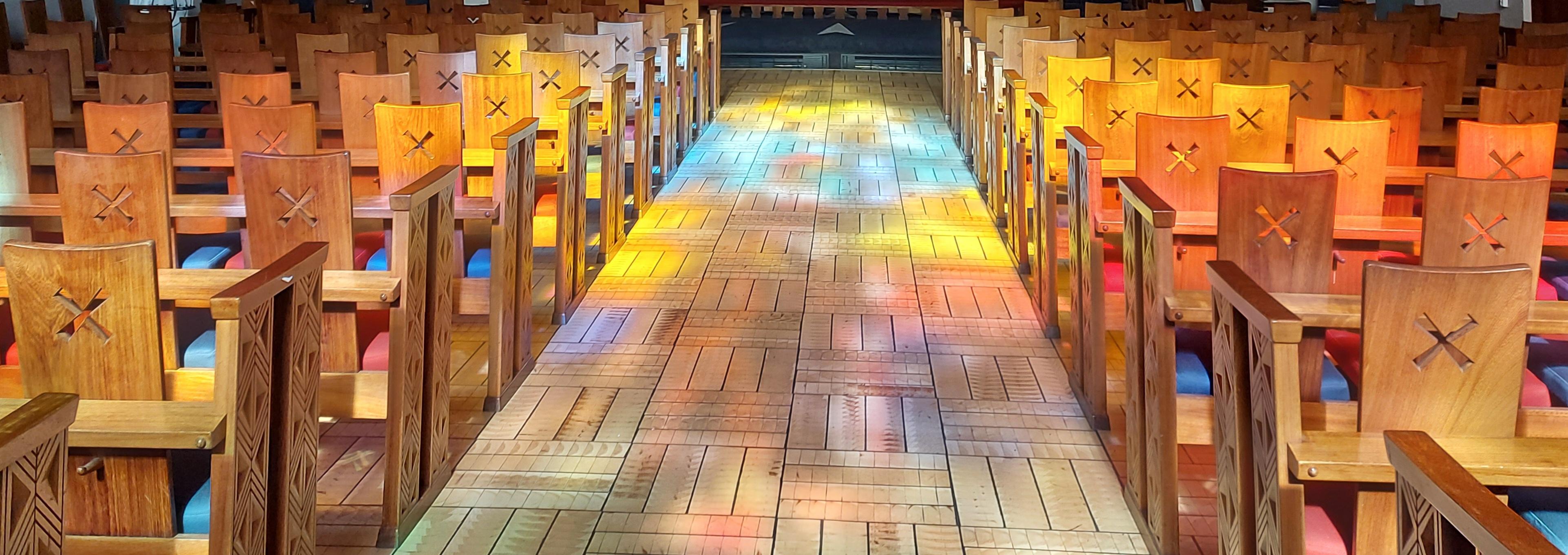 Solen skinner gjennom glassmaleriene i Torshov kirke og lager fargespill på gulvet. Foto: Hanne Slåtten