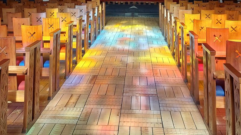Solen skinner gjennom glassmaleriene i Torshov kirke og lager fargespill på gulvet. Foto: Hanne Slåtten