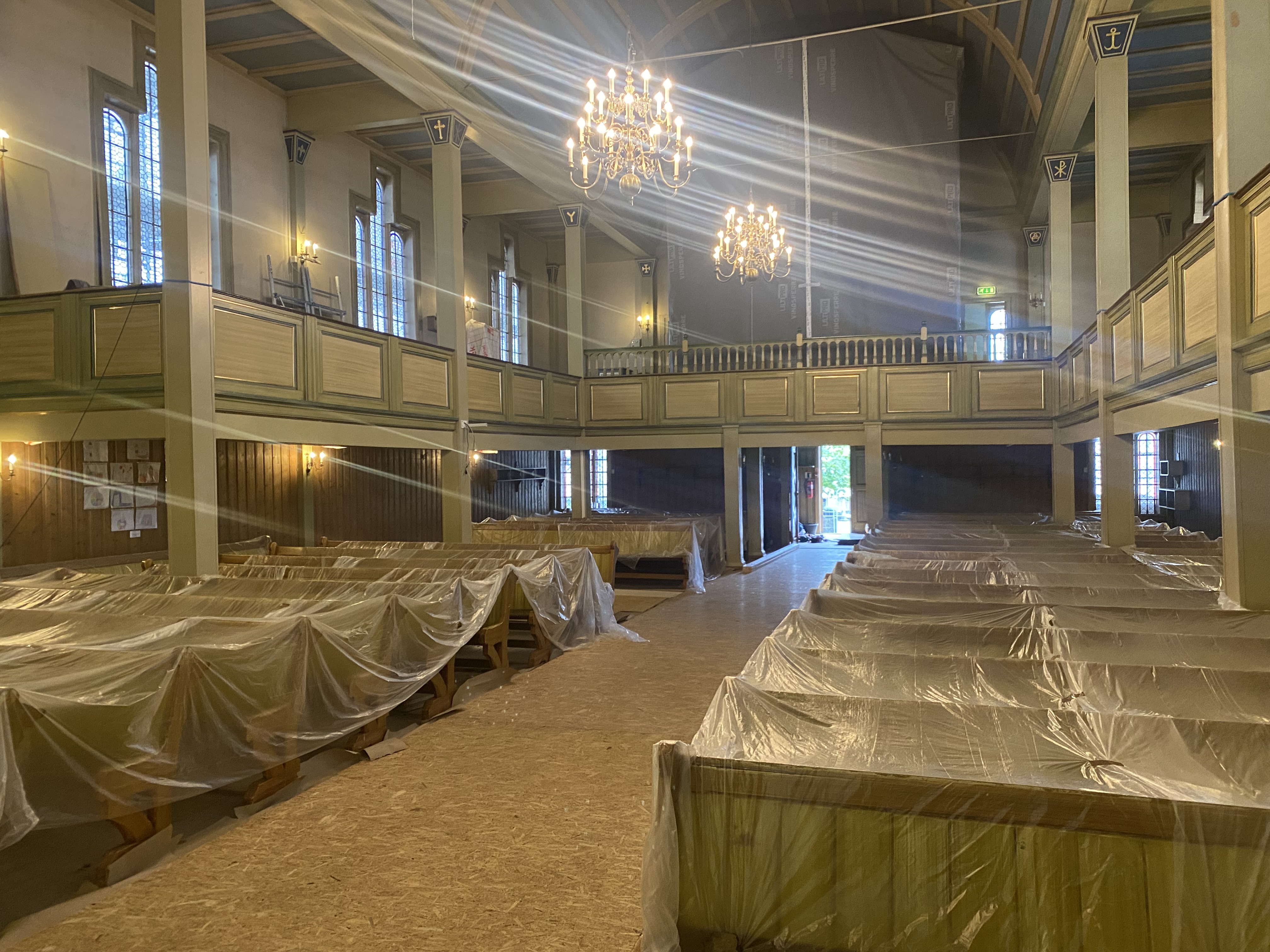 Inne i kyrkja er alle benkar dekket med plast, det raude teppet er under treplatar og orgelet er pakka inn.