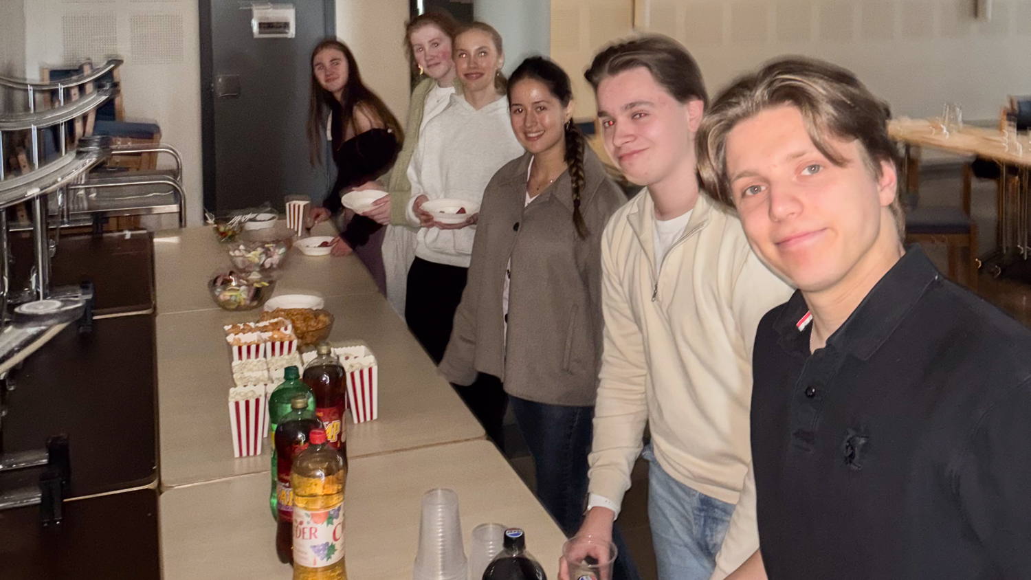 seks ungdommer står i en linje for å ta snack på et bord