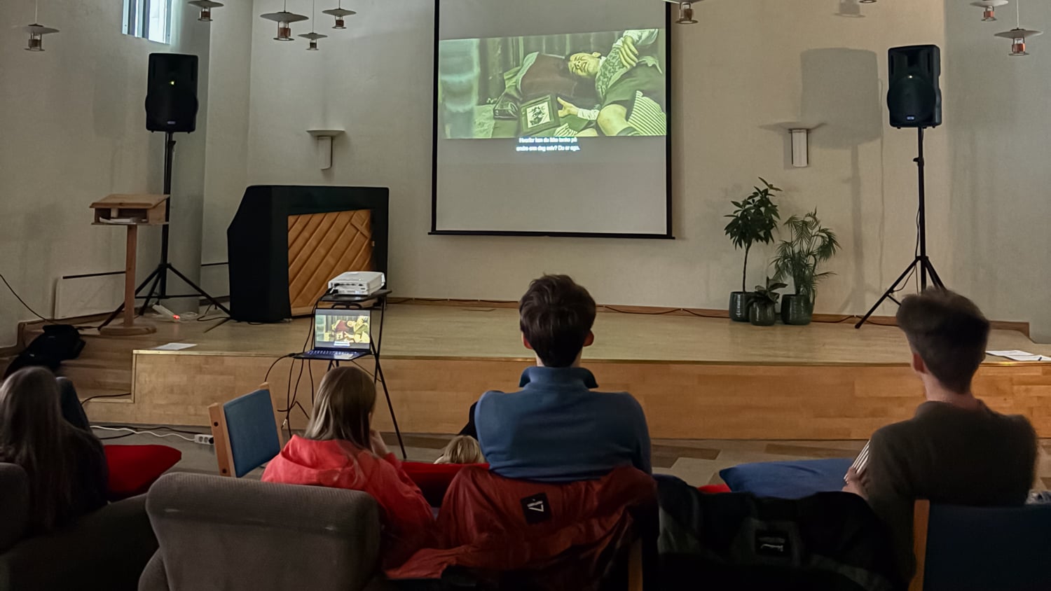 Ungdommer sett bakfra ser på film på et lerret