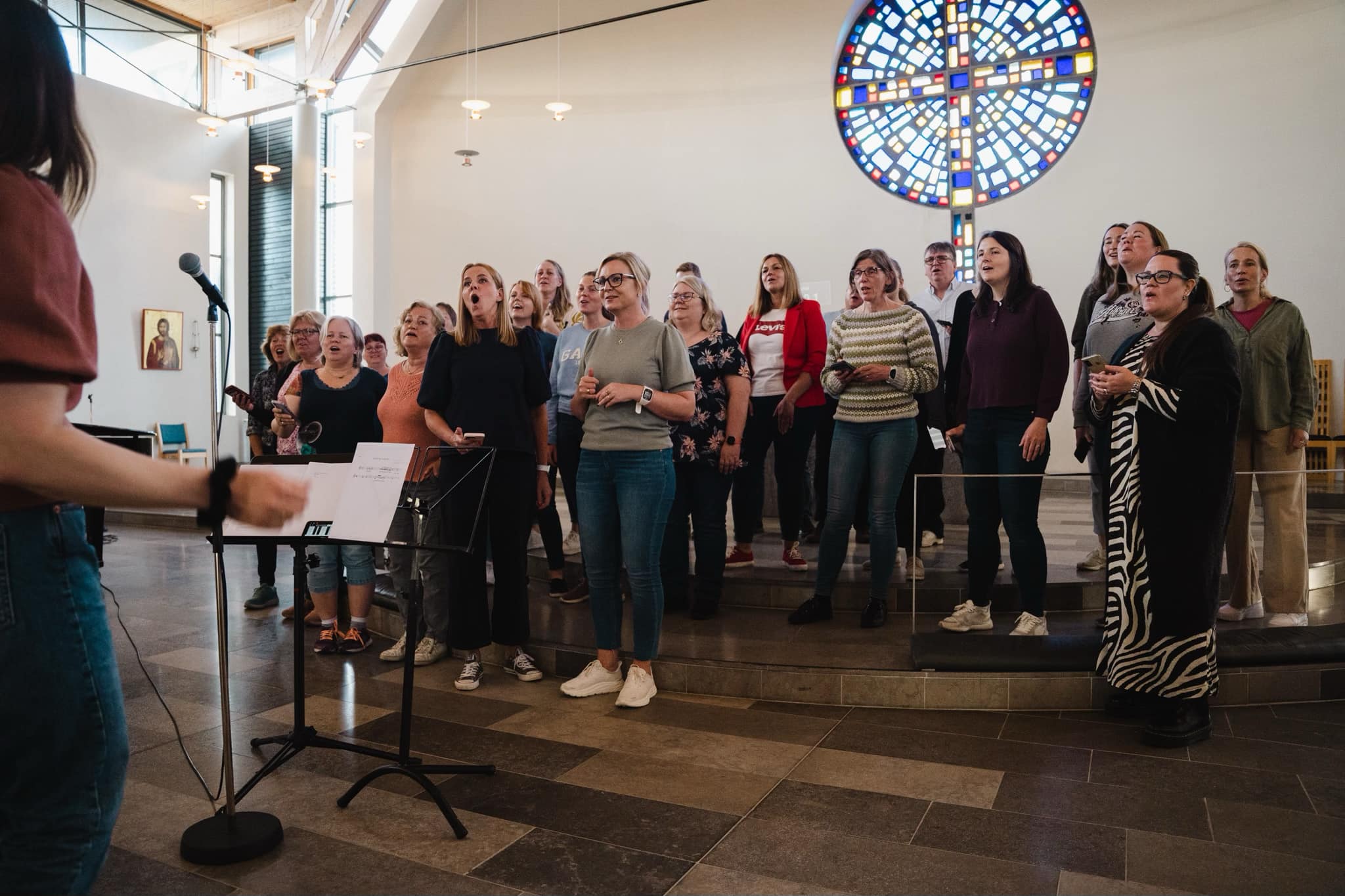 Gospelkoret str oppstilt framme i kyrkja og øver med ditigenten