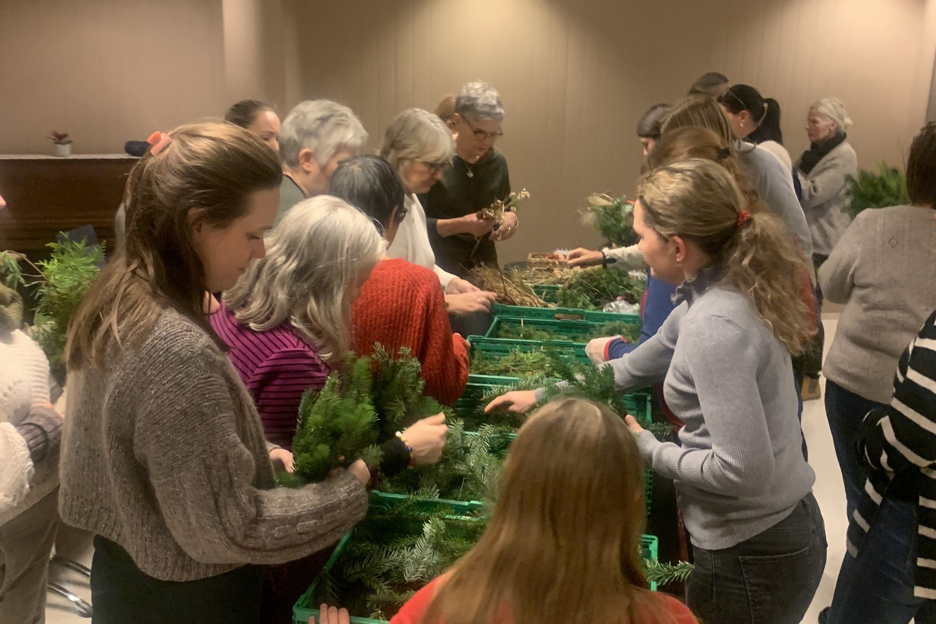 Mennesker går langs eit bord og plukker opp ting og greinar dei kan lage kransar med