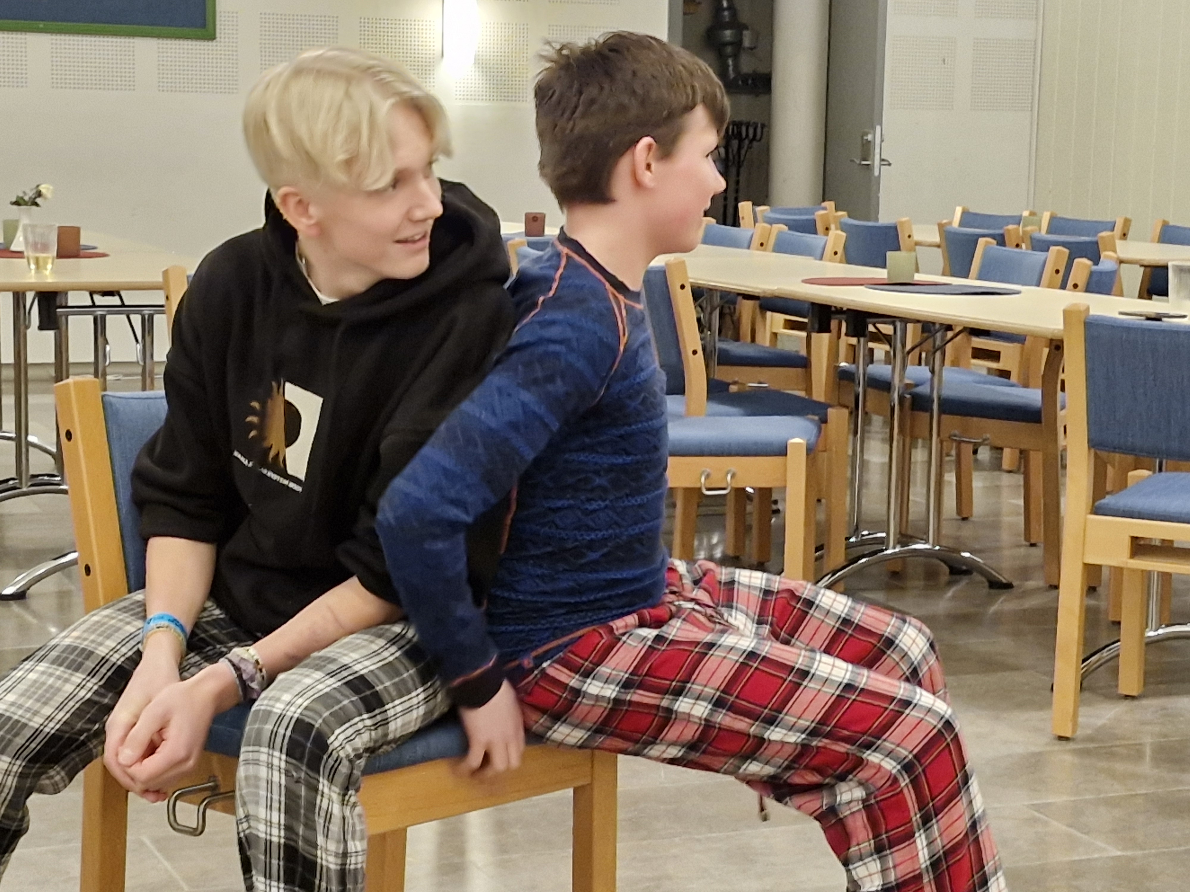 To ungdomsgutar sit på den siste stolen i stolleiken, den eine sitt meir på stolen en den andre