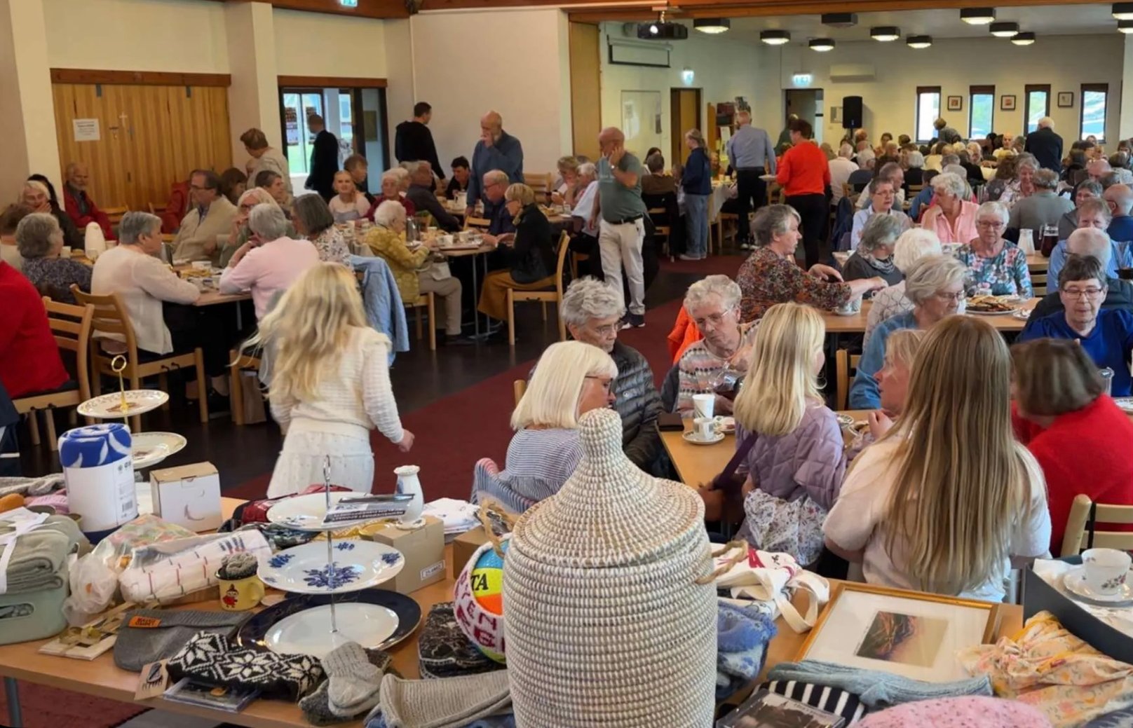 Mennesker sitter rundt bord i en helt full kirke