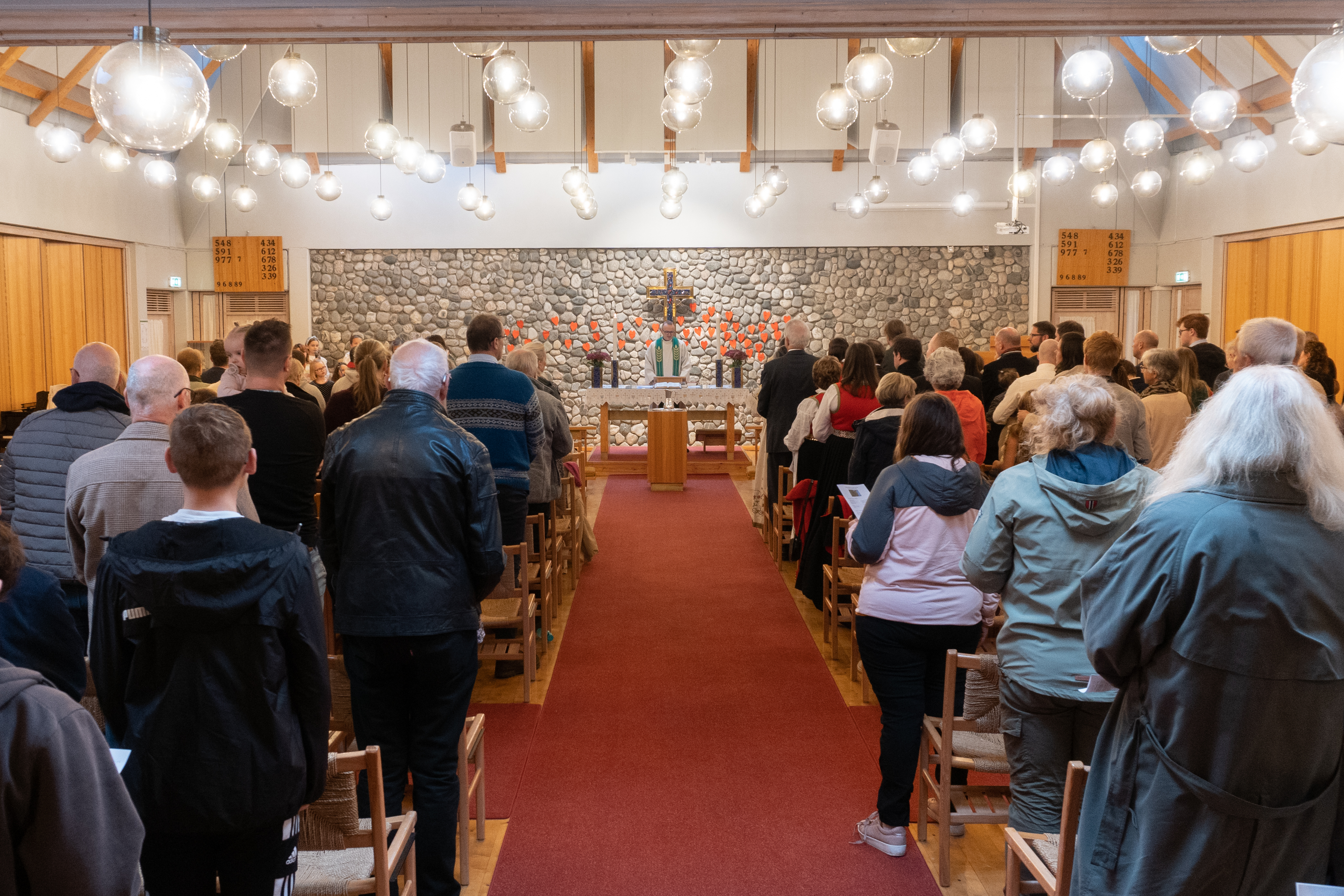 Det er fullsett gudsteneste i Landro kyrkje, vi ser opp midtgangen. Sokneprest Bjarte Nese står bak alteret