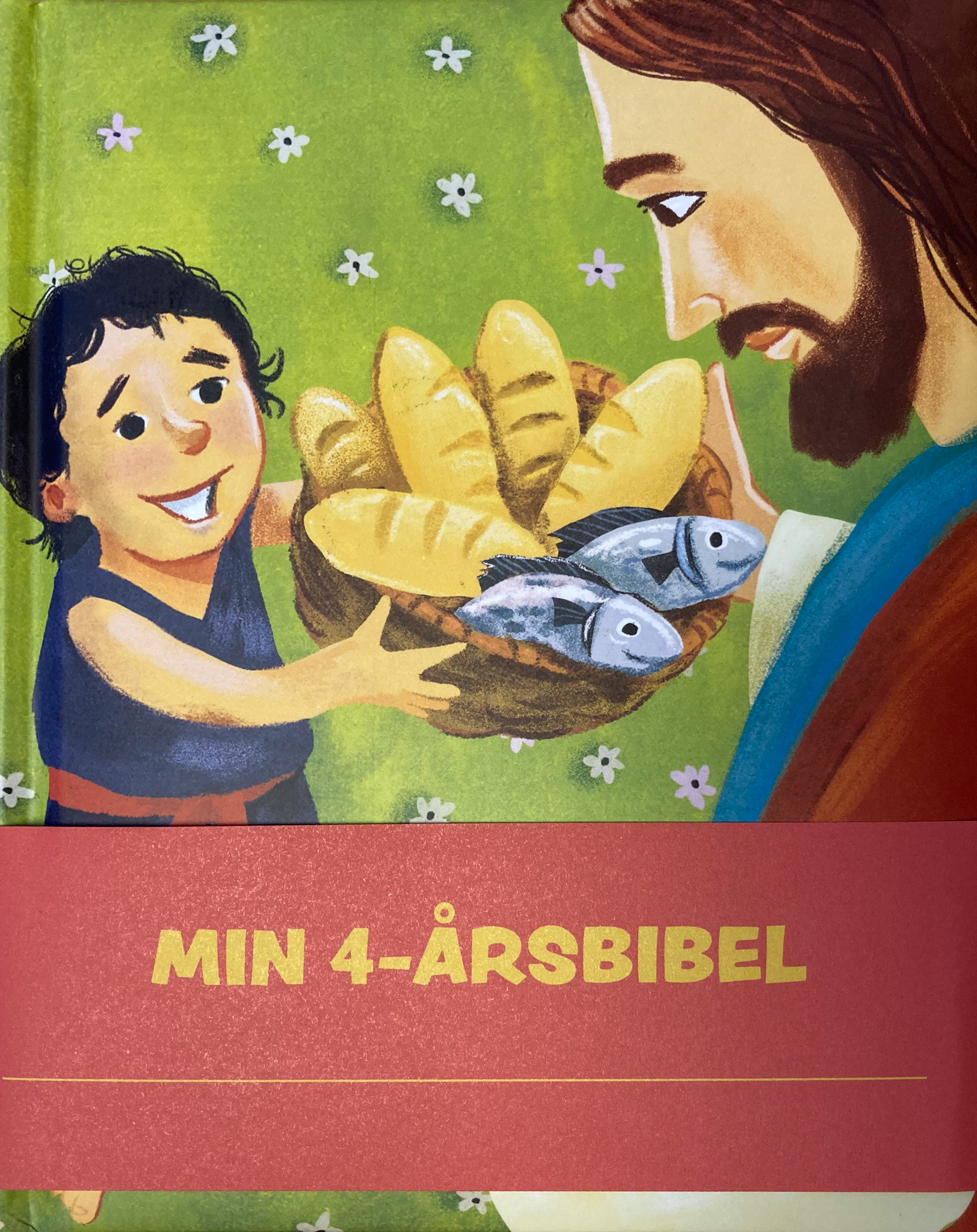 En bok, med en gutt som holder en kurv med fem br&oslash;d og to fisker mot jesus