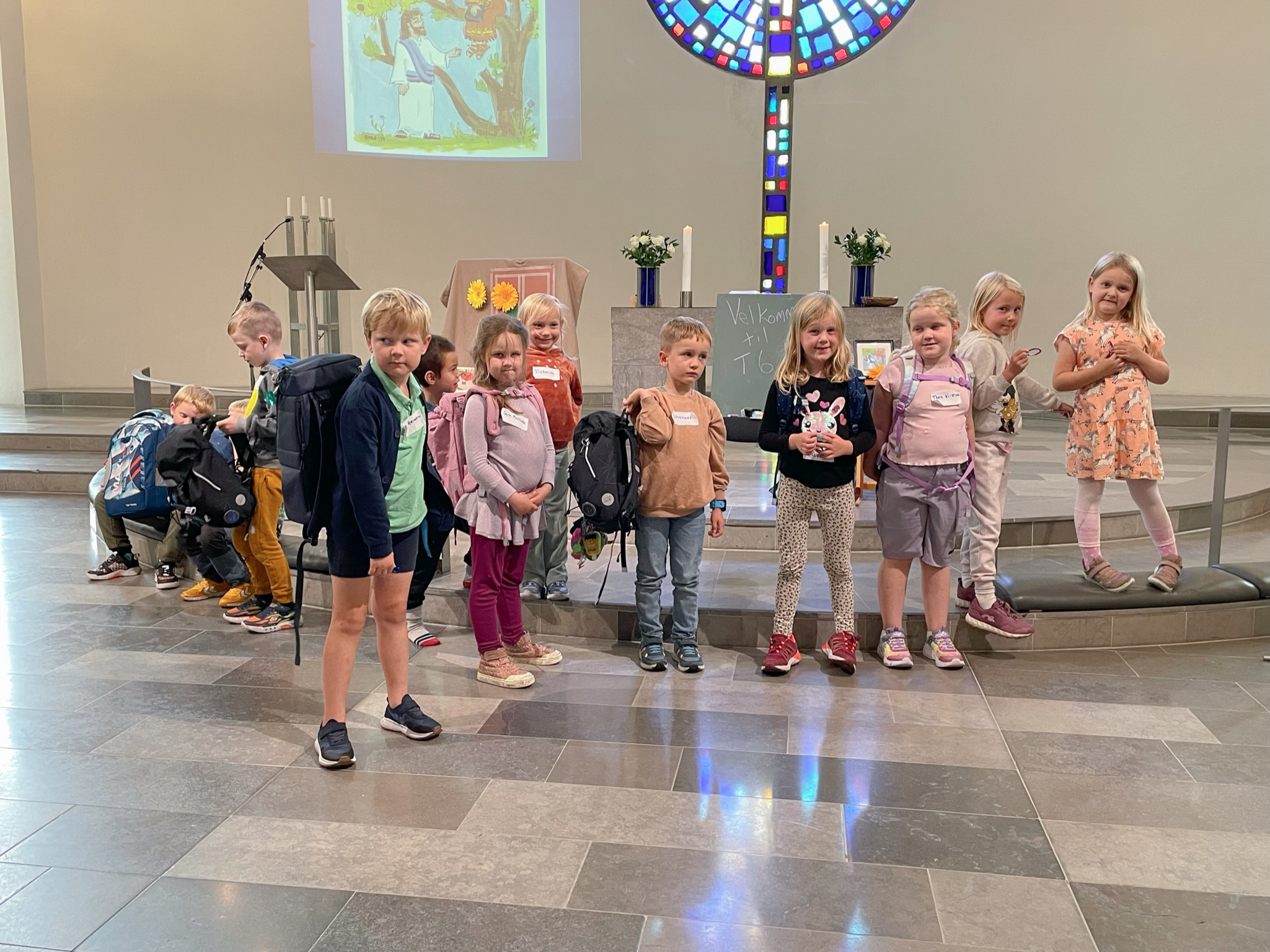 Flere førsteklassinger står fremme i Foldnes kyrke, dei har skulesekken på