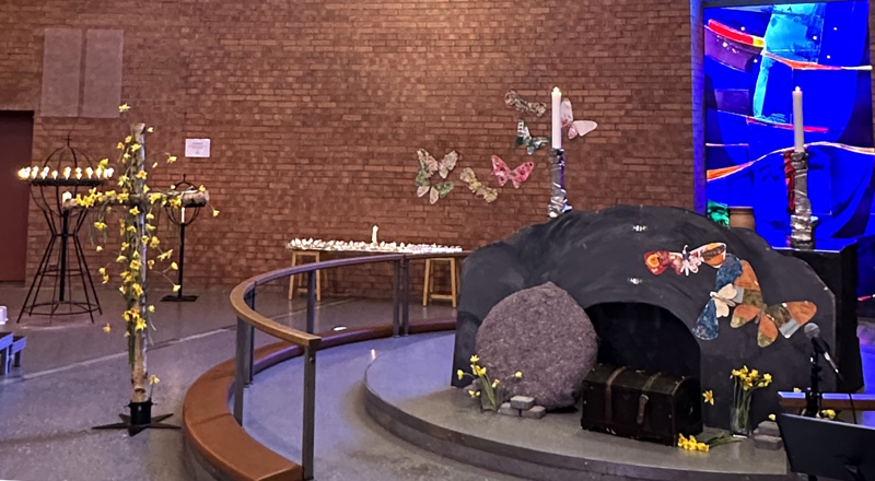 Påske med blomsterdekorert kors og åpen grav