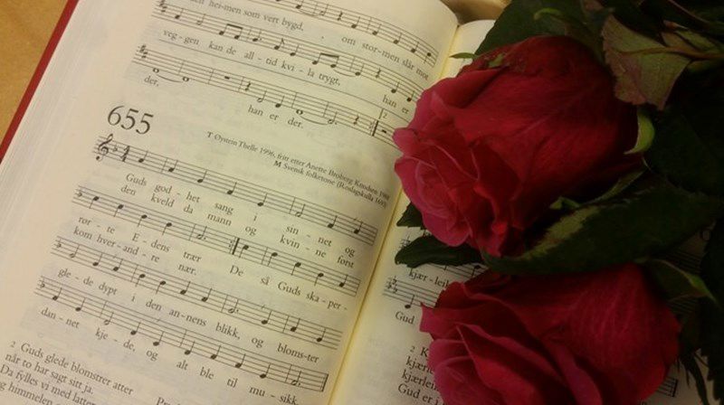 Åpen salmebok og en rose