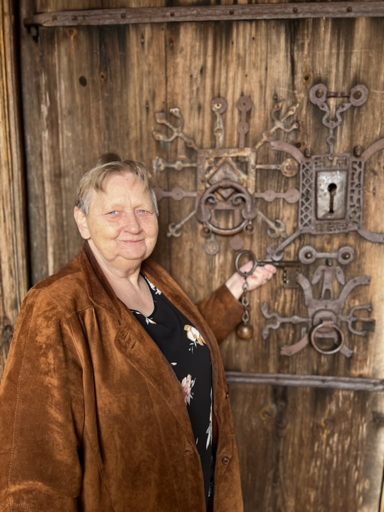 Omviser Marianne foran døra til Reinli stavkyrkje (Foto Anne Irene Stokke Bjørnstad)