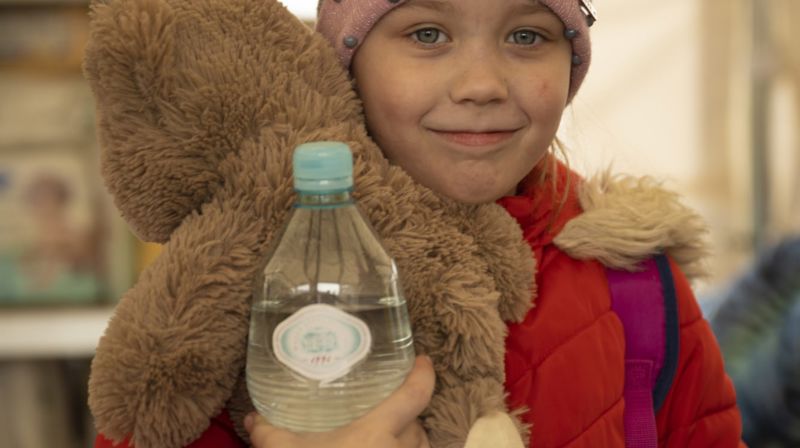 Bildet viser Sofia. Hun flyktet med mor og to søsken fra Cherkassy da flyalarmene gikk ustanselig. De er kommet til vår partner Polish Humanitarian Action og får vann og mat i det varme teltet