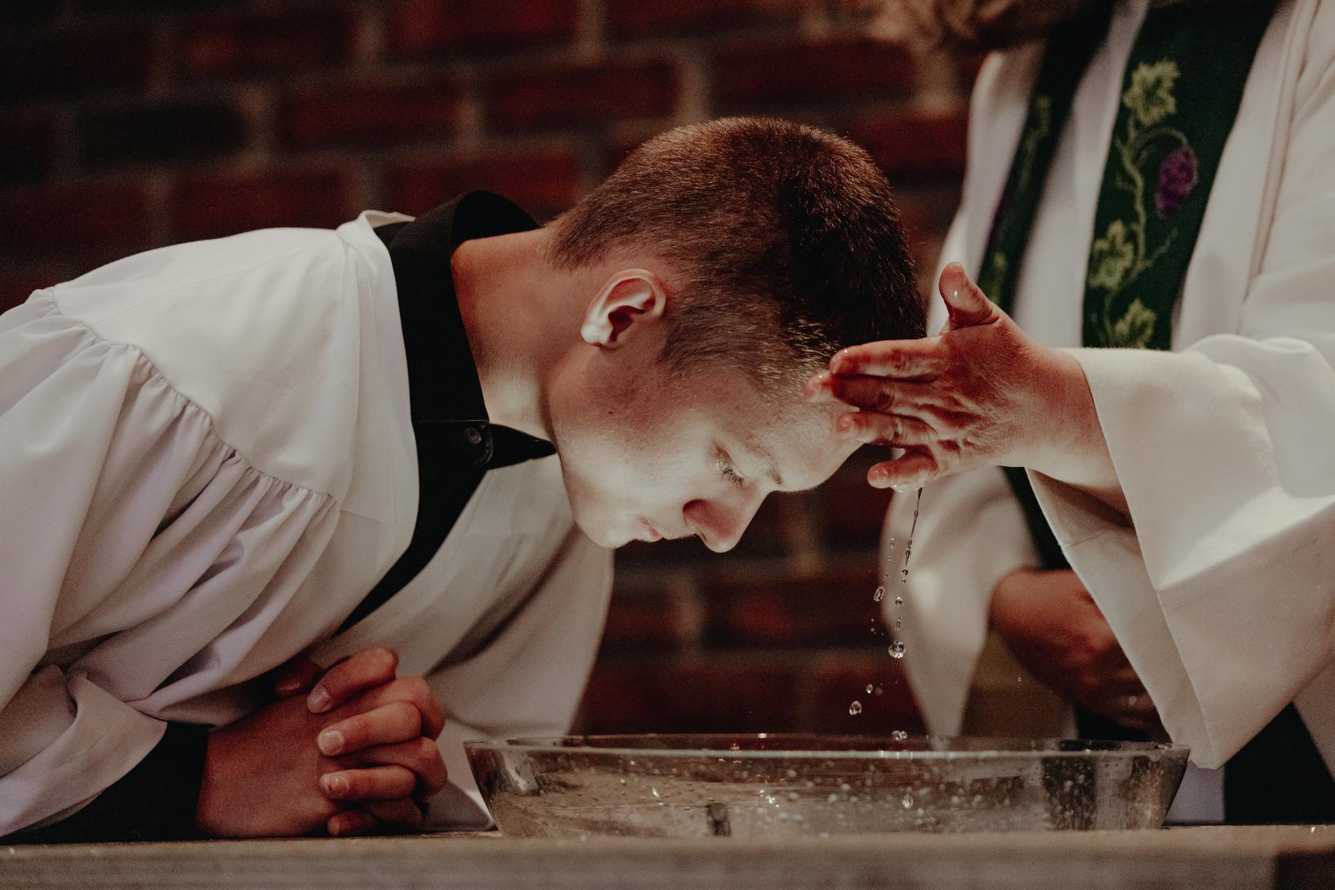 Ung mann døpes i hvit kappe i DNK.  Foto Malin