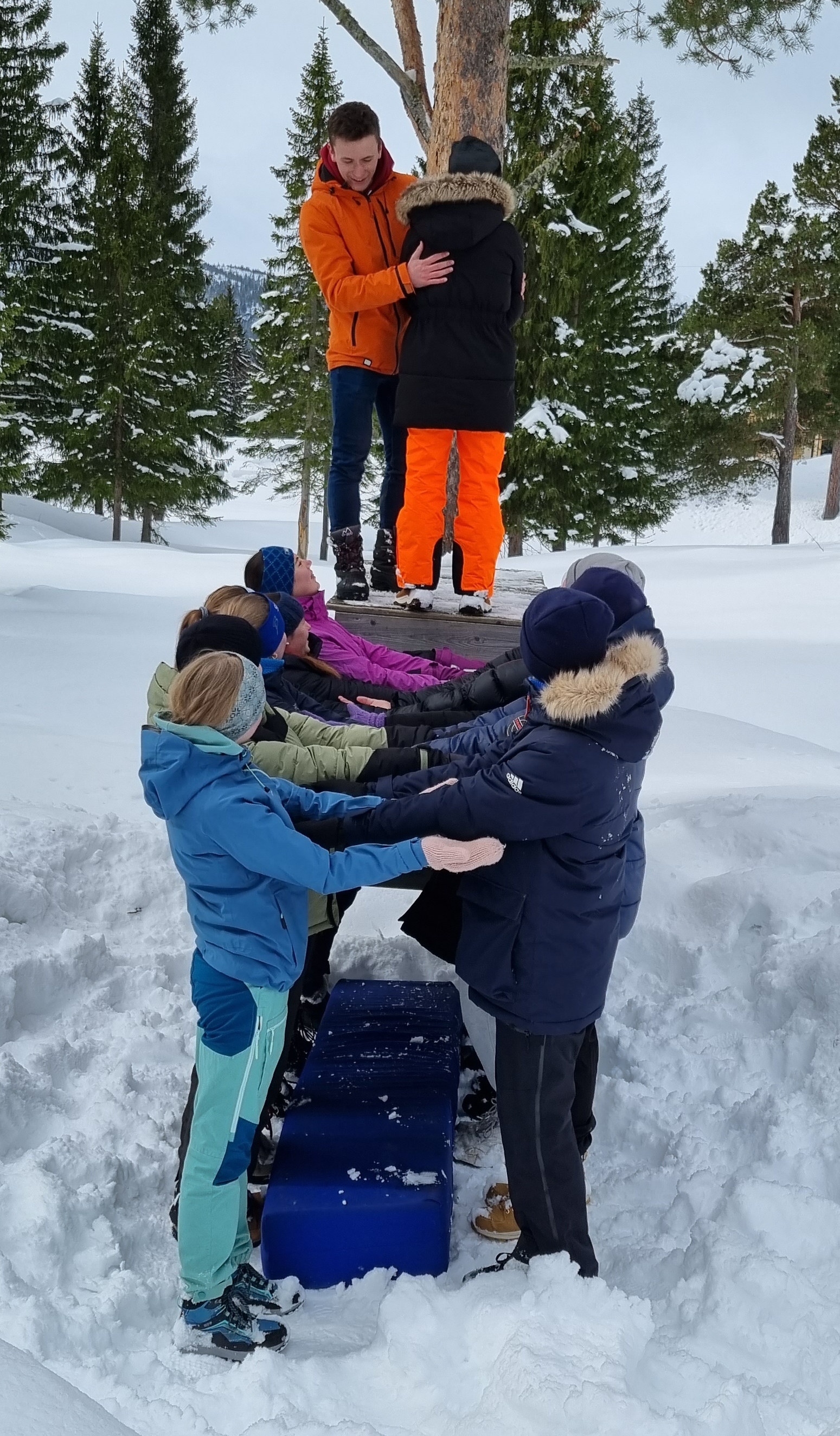 Leder og ungdommer i snøen gjør en felles øvelse