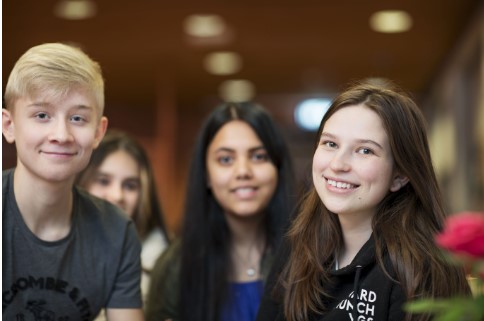 Fire ungdommer, en gutt og tre jenter, står sammen og smiler til kamera