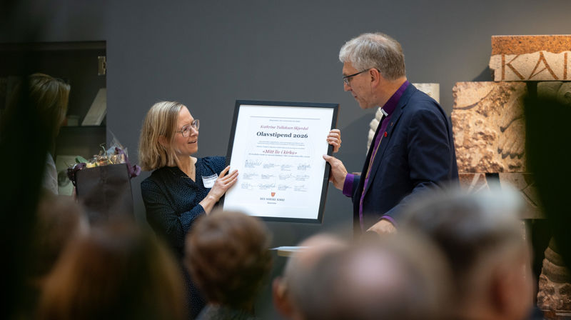 Katrine Tallaksen Skjerdal får stipendet overlevert av preses Olav Fykse Tveit i Kirkens hus. (Foto: Den norske kirke)