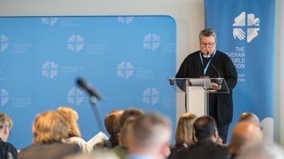 Kristine Sandmæl på talerstolen i LVF sitt rådsmøte i juni 2026. Foto: Albin Hillert / LWF.