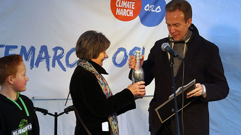 Biskop Helga Haugland Byfuglien overrakte utenriksminister Børge Brende en flaske med vann som klimapilegrimene har båret med seg siden den første vandringen på Svalbard i juni i år. Til venstre: Victor fra Miljøagentene.