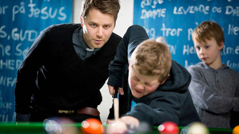 Diakon Arild Tjørve i Vågsbygd kirke spiller biljard med noen ungdommer.